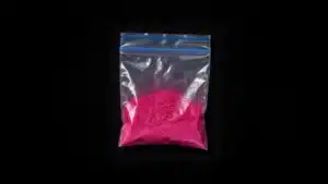 Bolsa de plástico transparente con polvo rosa de tusi sobre fondo negro