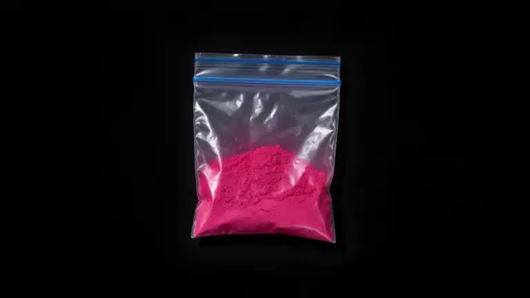 Bolsa de plástico transparente con polvo rosa de tusi sobre fondo negro