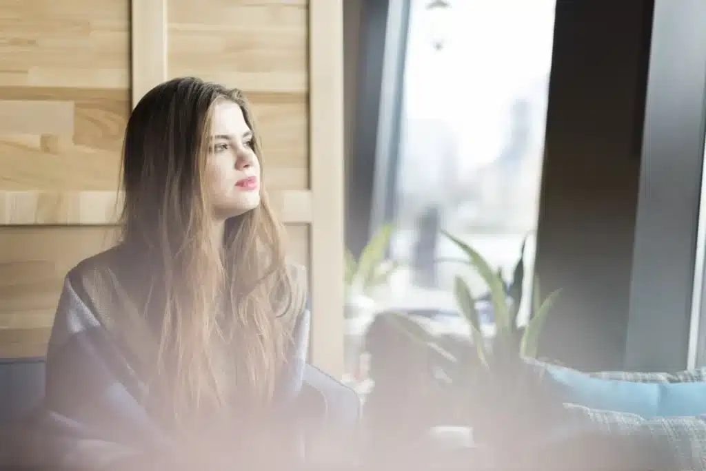 Mujer pensativa mirando por la ventana, imagen sobre patología dual y salud mental