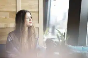 Mujer pensativa mirando por la ventana, imagen sobre patología dual y salud mental